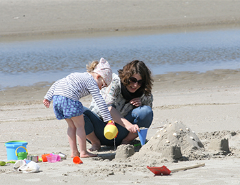 Mutter und Kind bauen am Strand Sandschlösser